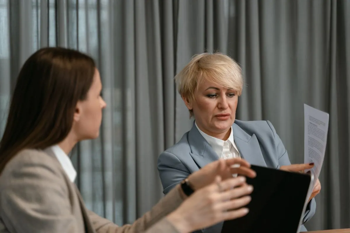 Two people sitting opposite each other in a meeting room, having a serious conversation