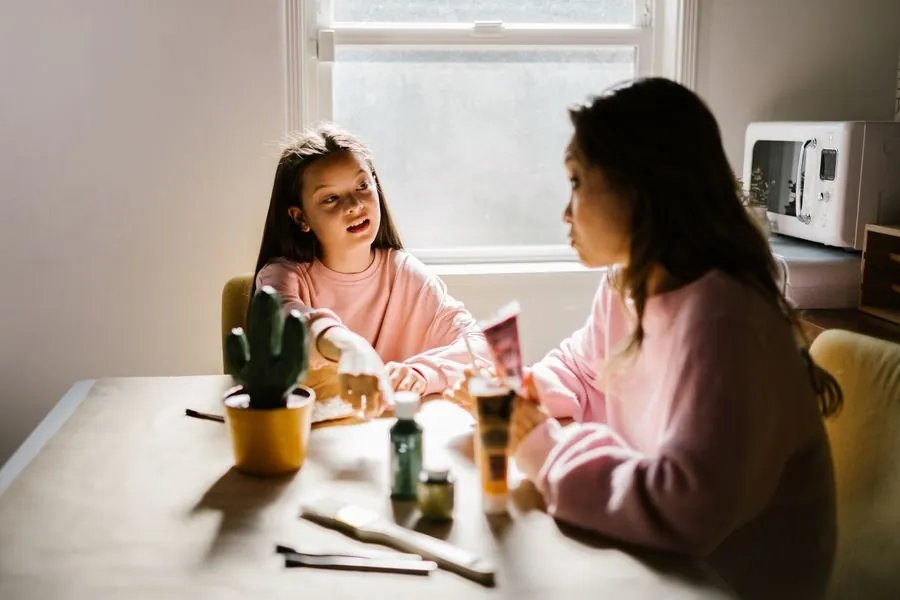 A mother talking with her daughter at the kitchen table