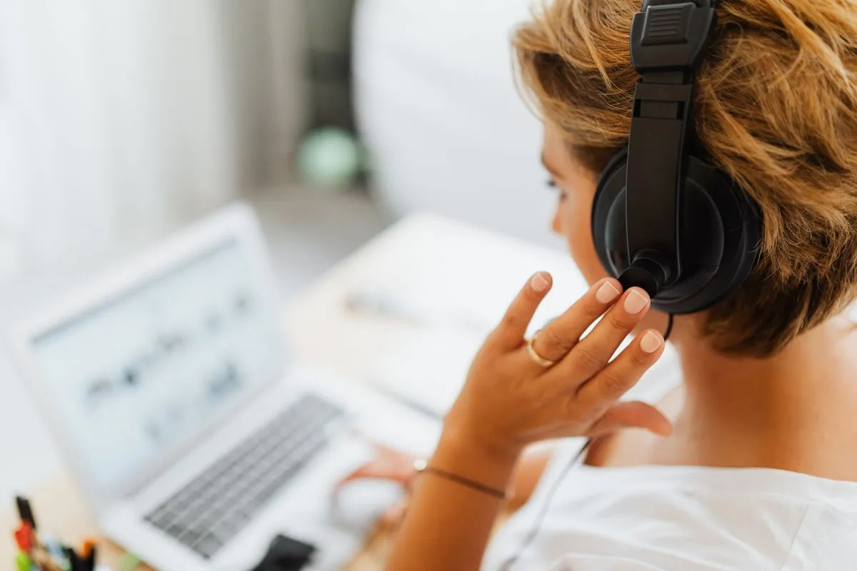 A person with headphones working at a laptop