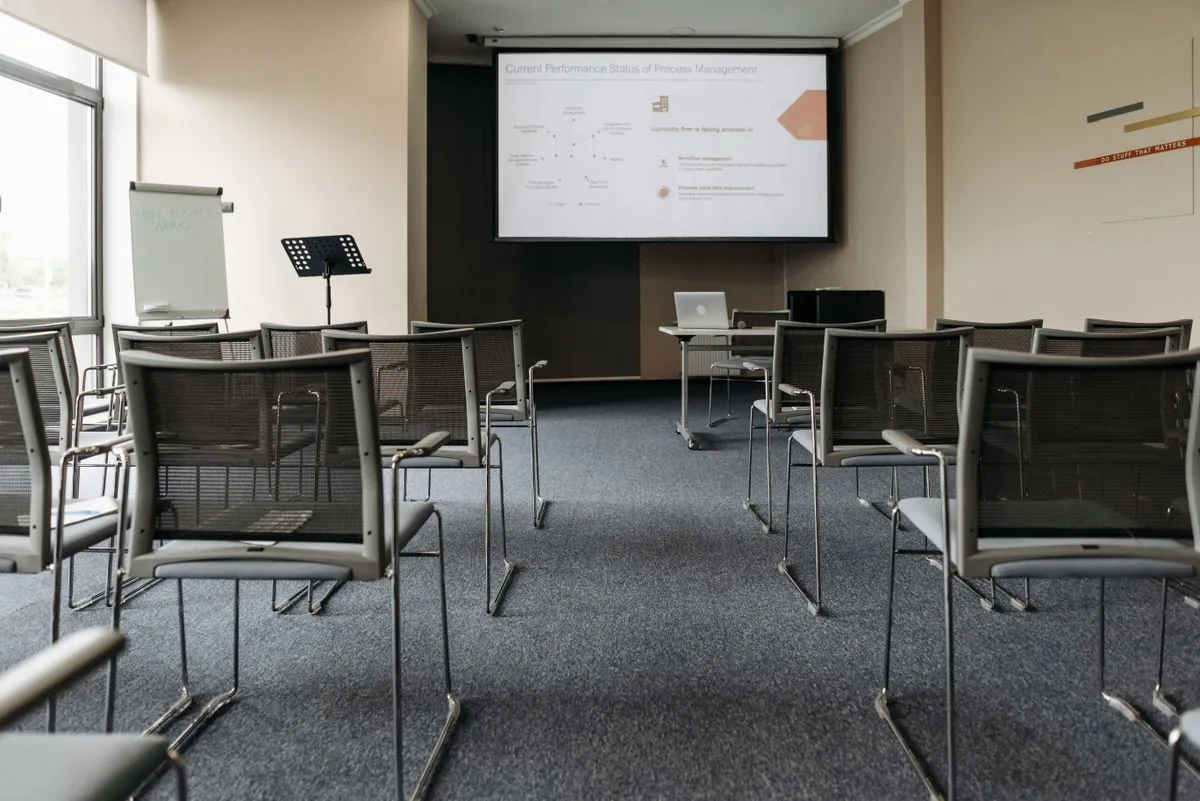 An empty training room with the projector screen down and chairs in rows